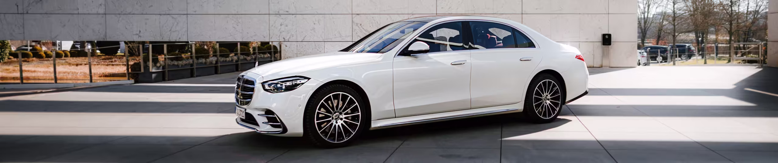 MB Rent weiße S-Klasse steht vor hellem Gebäude