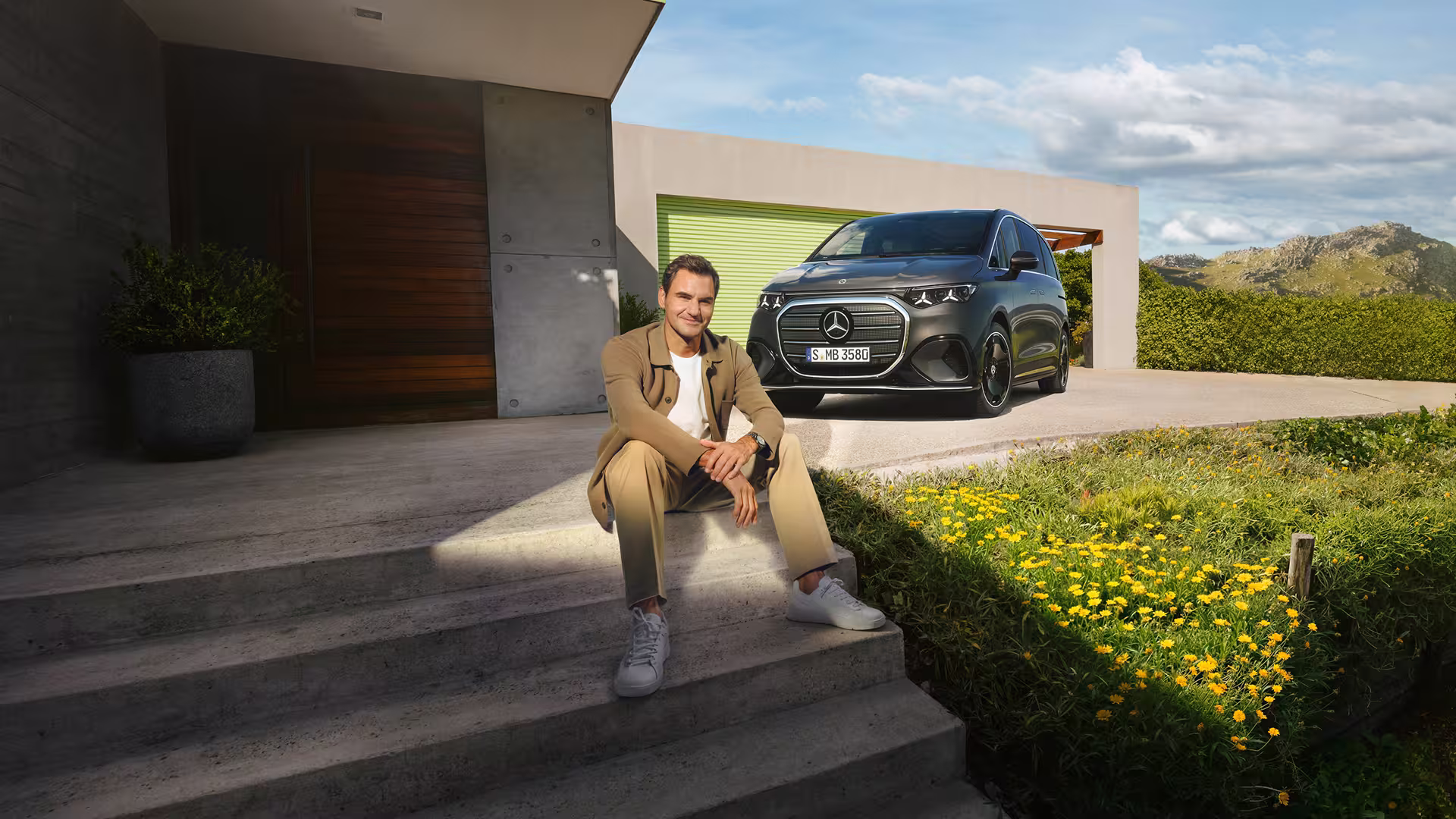 Mercedes Benz VLE 2026 - Mann sitzt bei sonnigem Wetter auf Treppe, im Hintergrund der VLE zu sehen